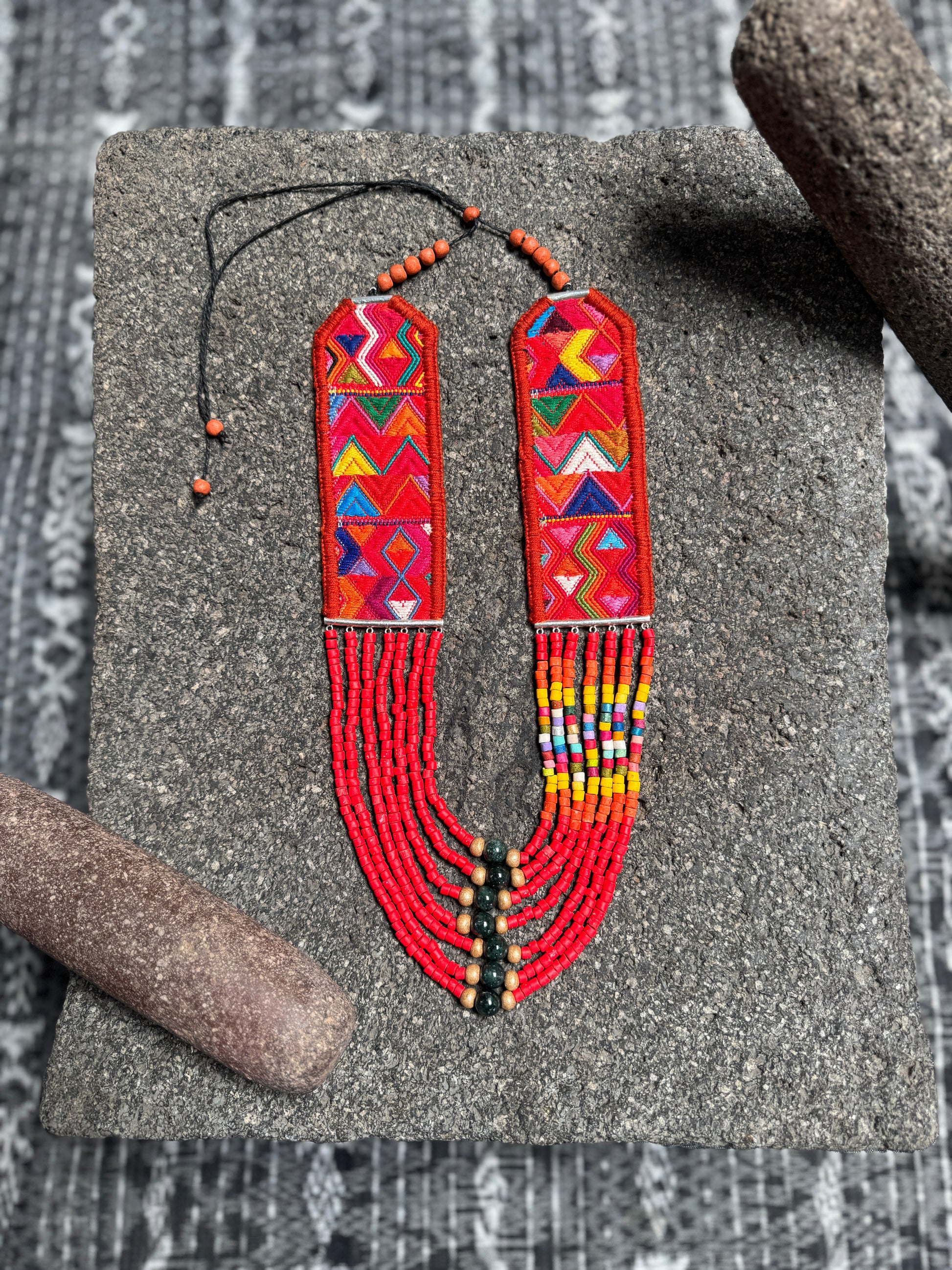 Colorful beaded necklace with geometric patterns on a textured surface