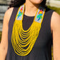 Woman wearing a black sleeveless top with colorful parrot designs and a yellow beaded necklace, outdoors.