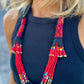 Woman wearing a wide-brimmed hat and colorful beaded necklaces with a blurred background