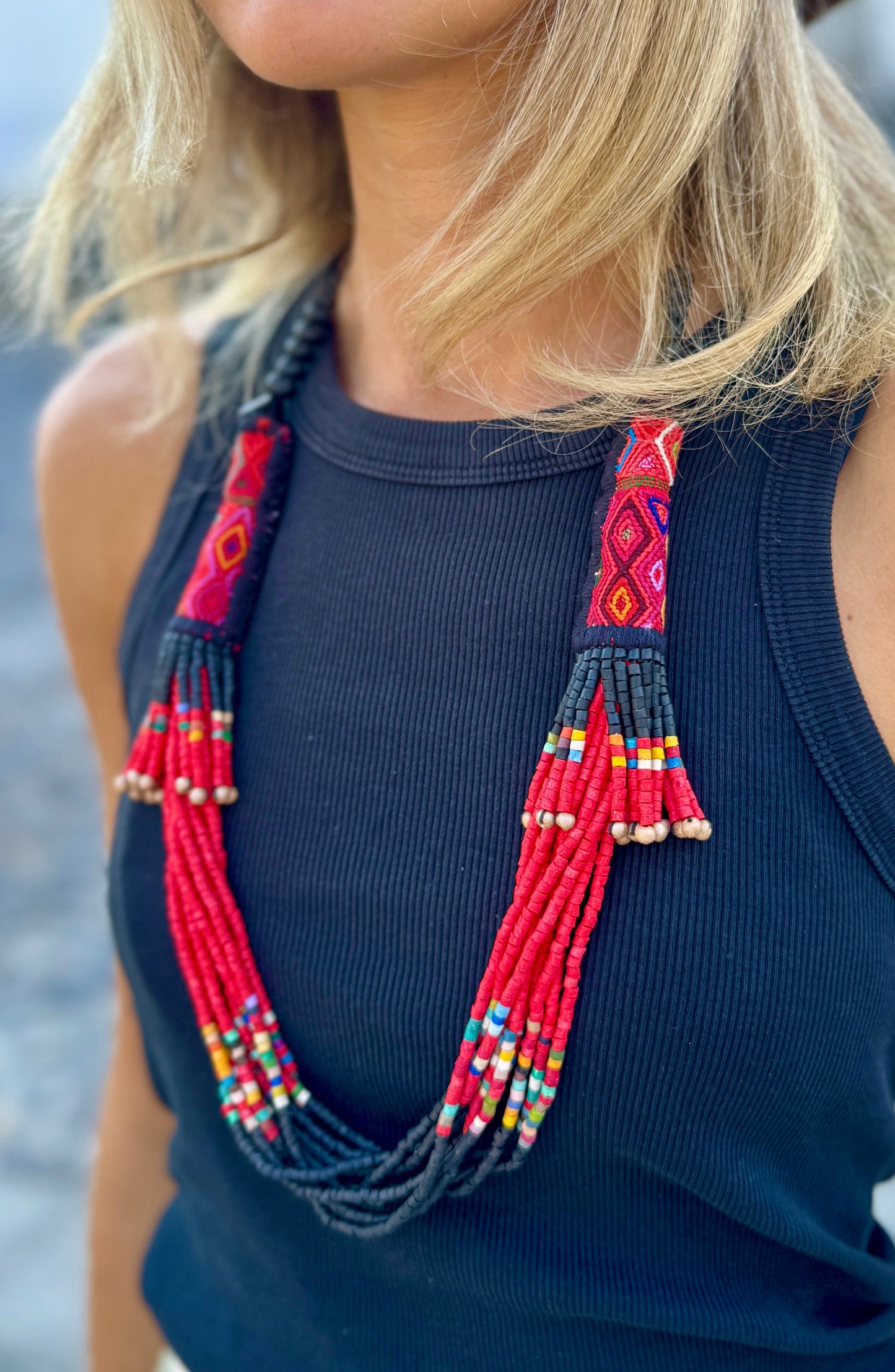 Woman wearing a wide-brimmed hat and colorful beaded necklaces with a blurred background