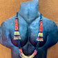 Beaded necklace displayed on a mannequin bust against a brown background
