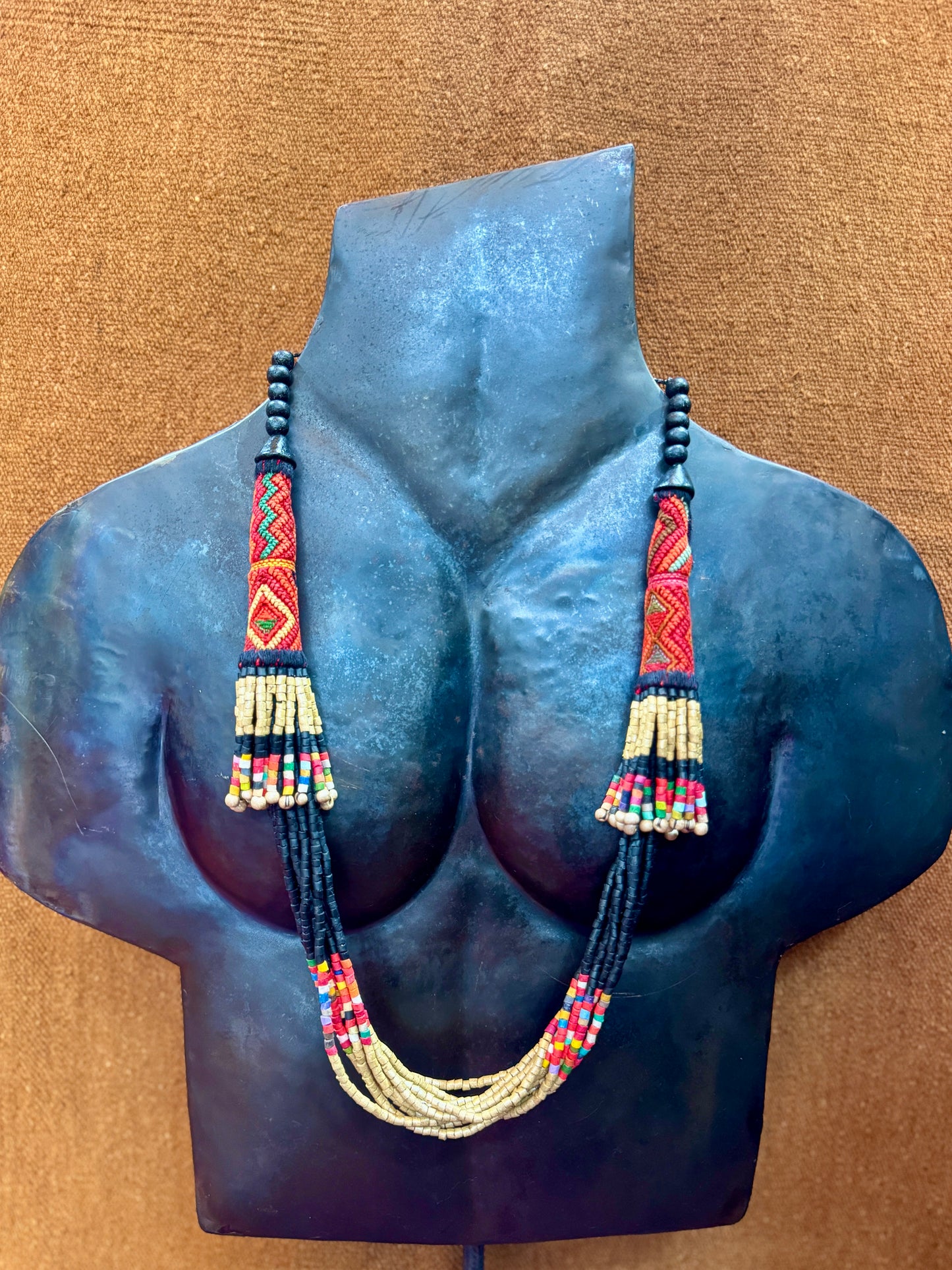 Beaded necklace displayed on a mannequin bust against a brown background