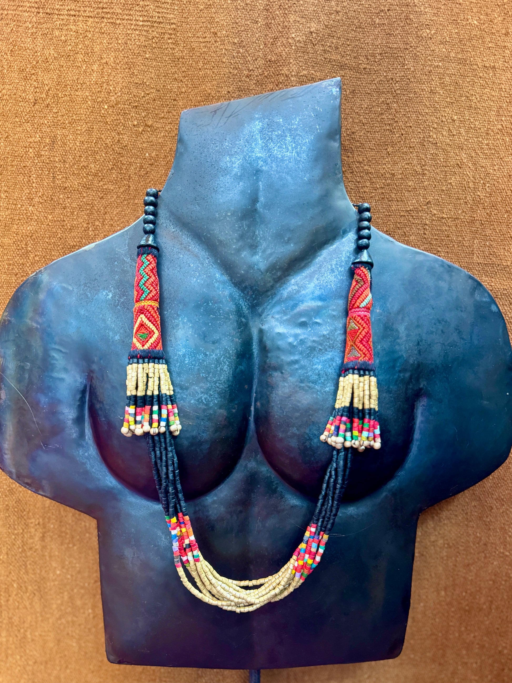 Beaded necklace displayed on a mannequin bust against a brown background