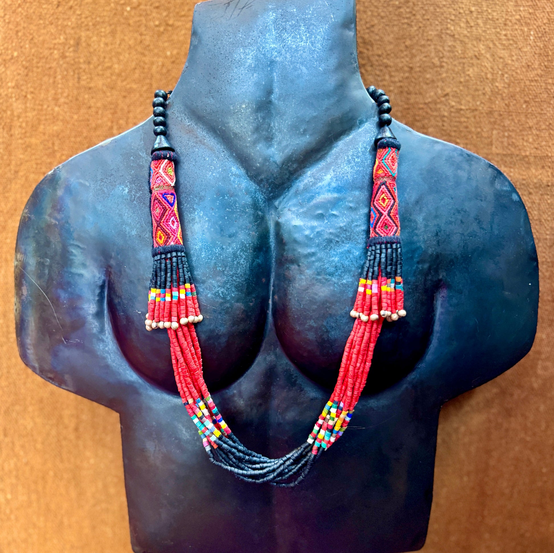 Necklace with colorful beads on a mannequin bust against a brown background