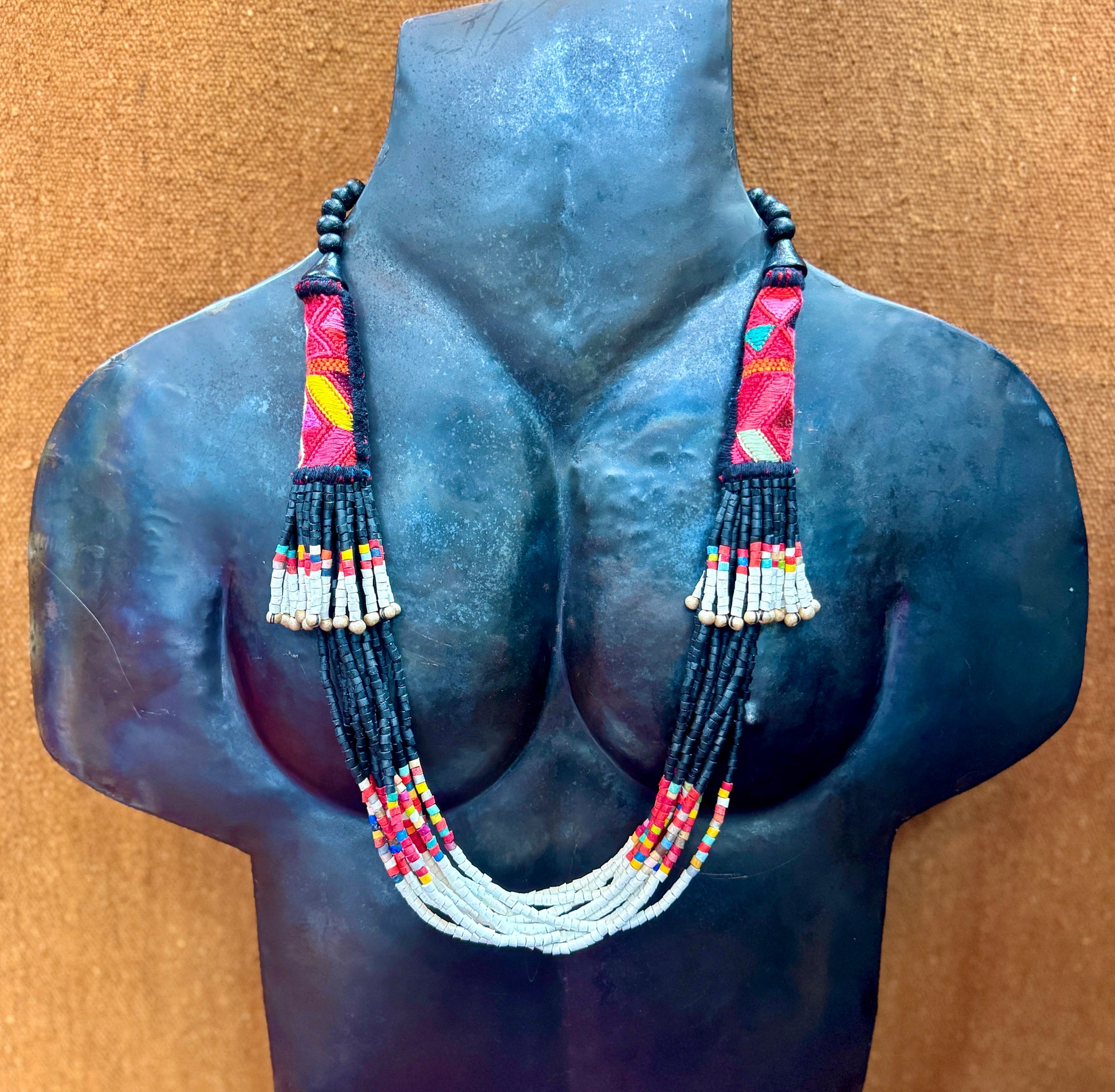 Necklace with colorful beads on a mannequin bust against a brown background